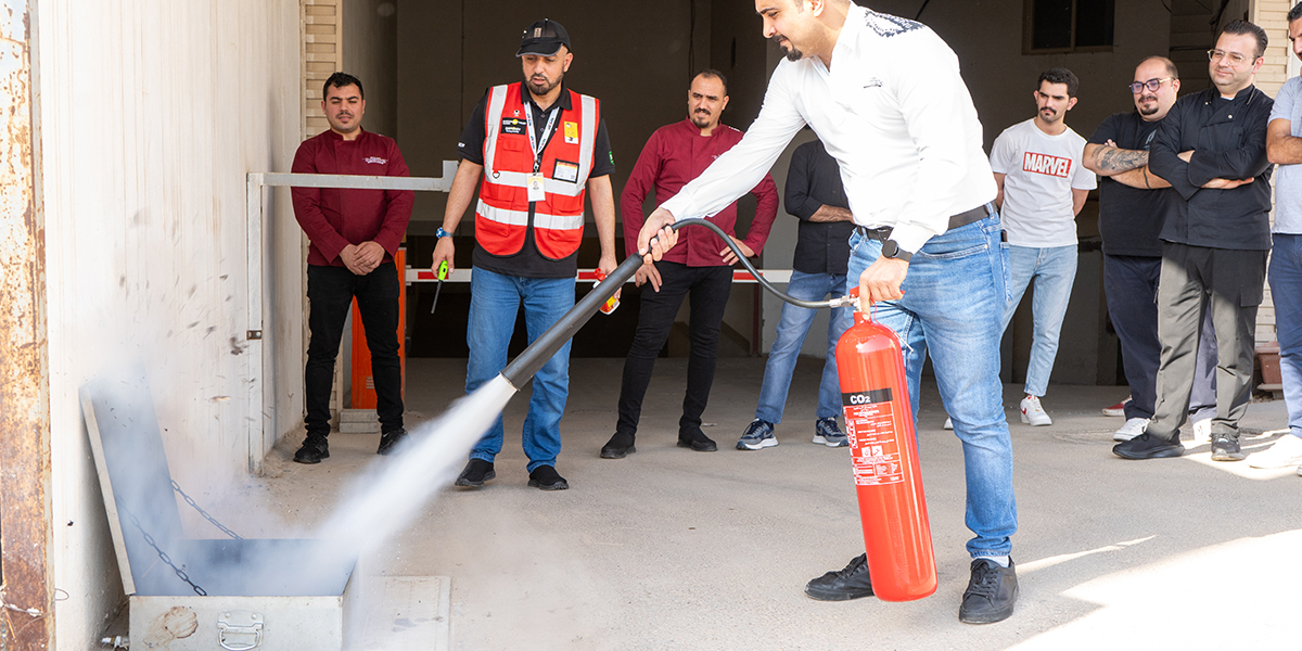 Employee demonstrating fire extinguisher use during fire safety training in Saudi Arabia